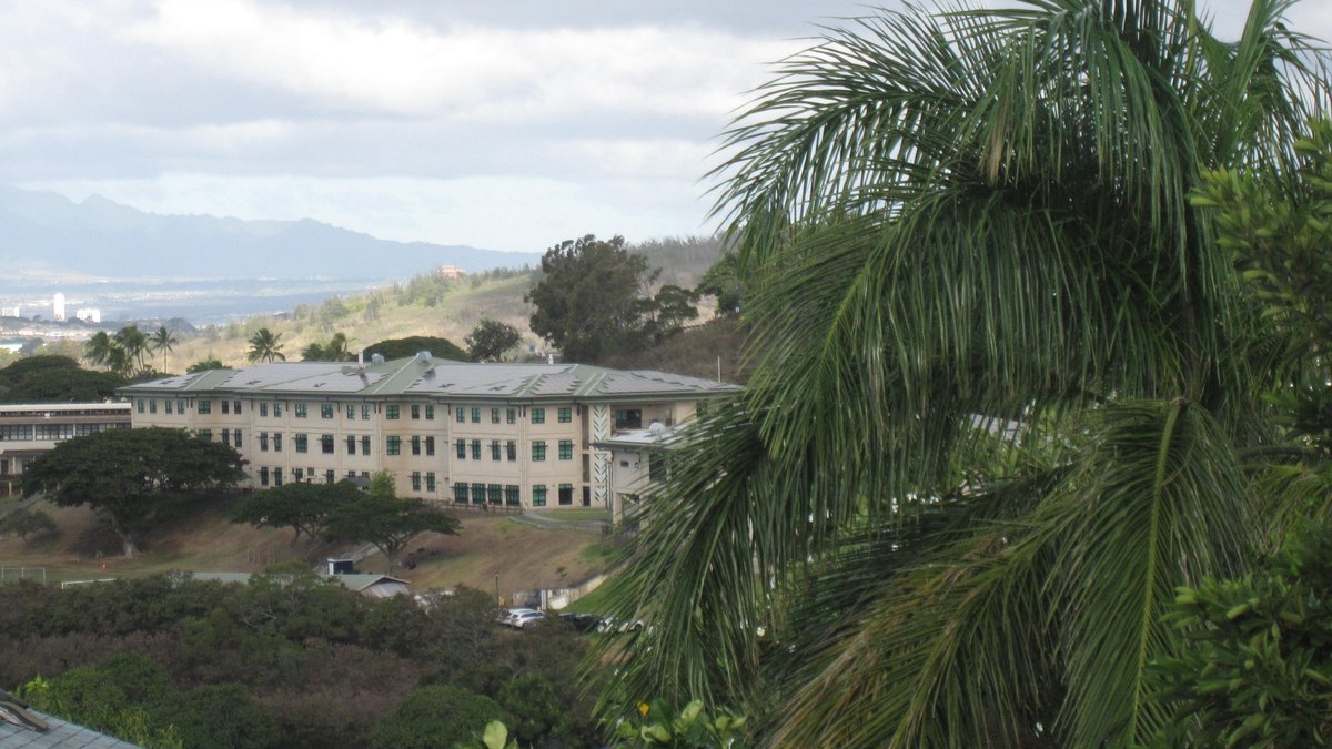 Buildings of the Kamehameha Schools Kapalama campus on a green hillside above Honolulu with mountains beyond