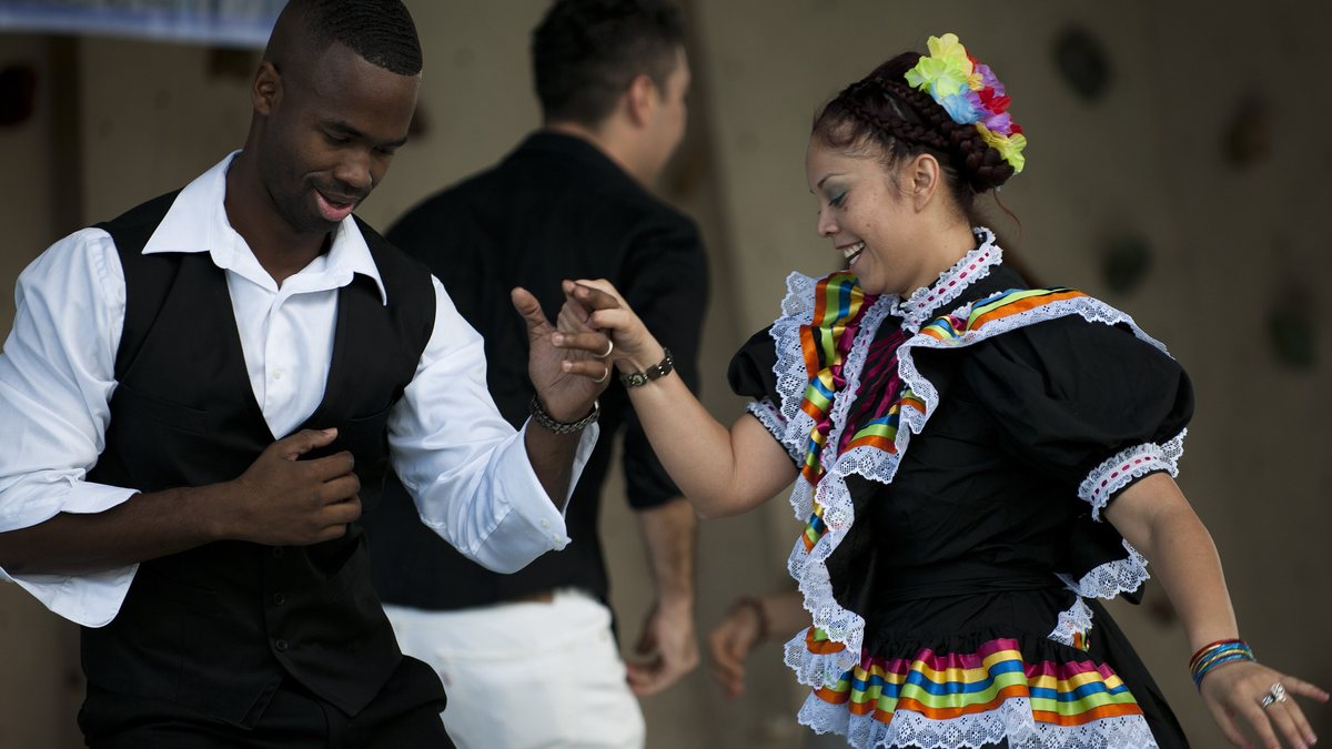 Dancers in traditional Mexican folklórico costumes performing at a Hispanic Heritage Month festival