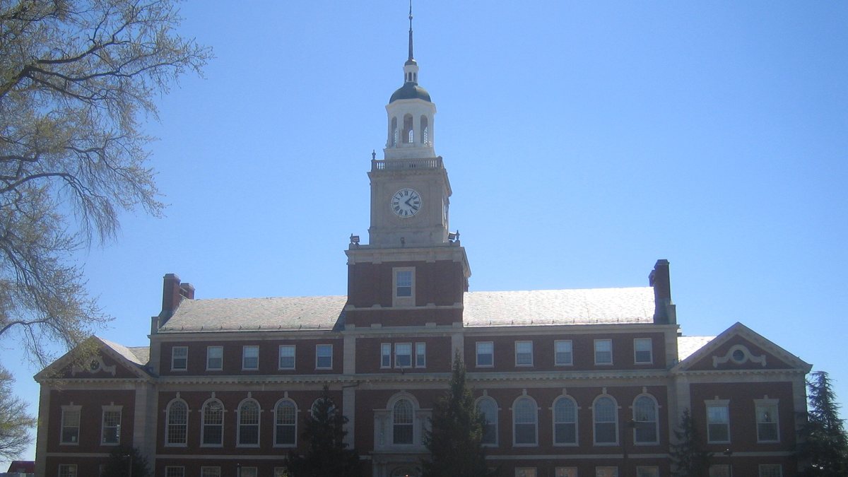Founders Library at Howard University with its brick clock tower rising above the campus under a clear blue sky