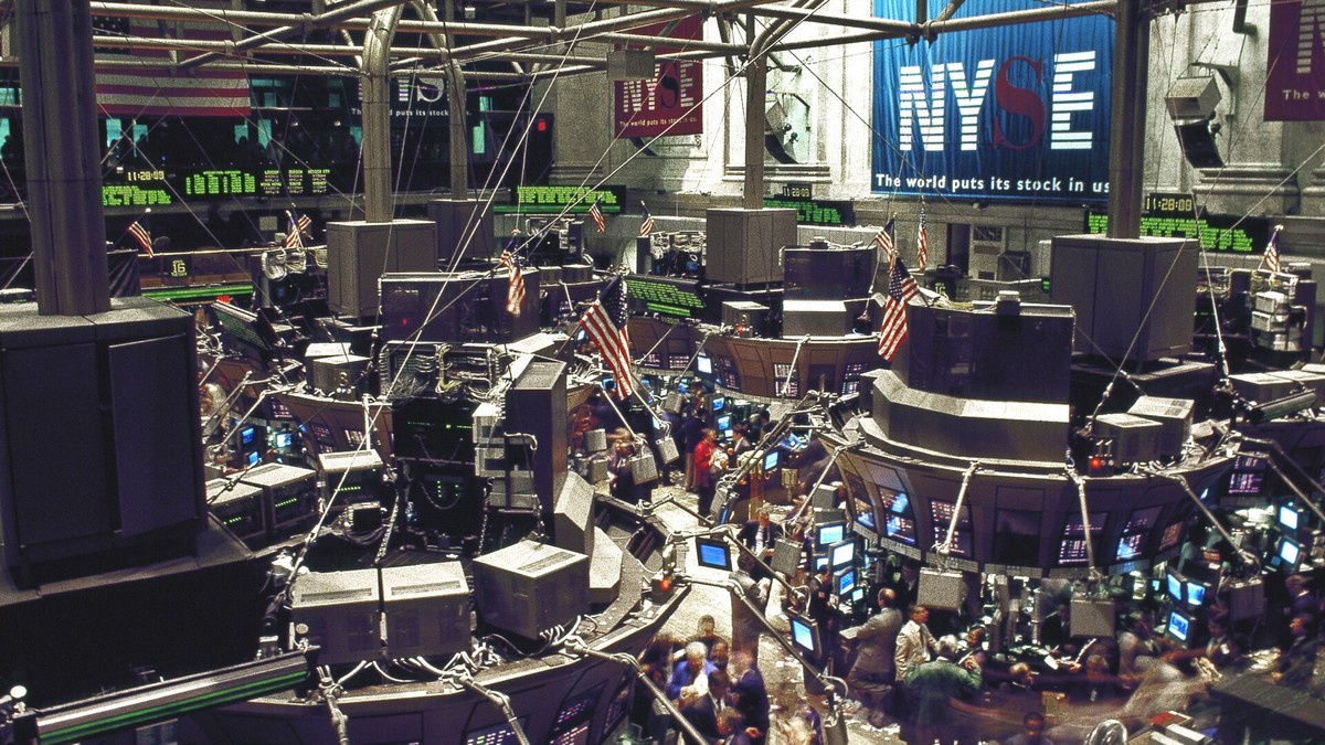 Traders working below rows of screens and American flags on the New York Stock Exchange trading floor