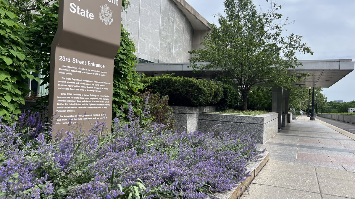 The entrance sign and landscaped walkway outside the US Department of State headquarters in Washington on a spring day