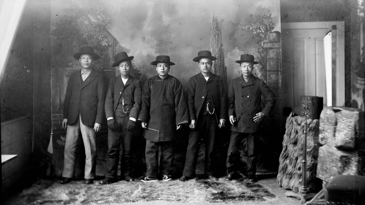 Black-and-white 1890s studio portrait of a group of Chinese American men in dark jackets and hats