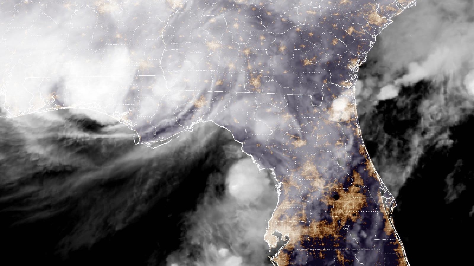 Night satellite view of the storm's clouds spreading over Alabama and the Florida Panhandle at landfall with city lights glowing across Georgia and Florida
