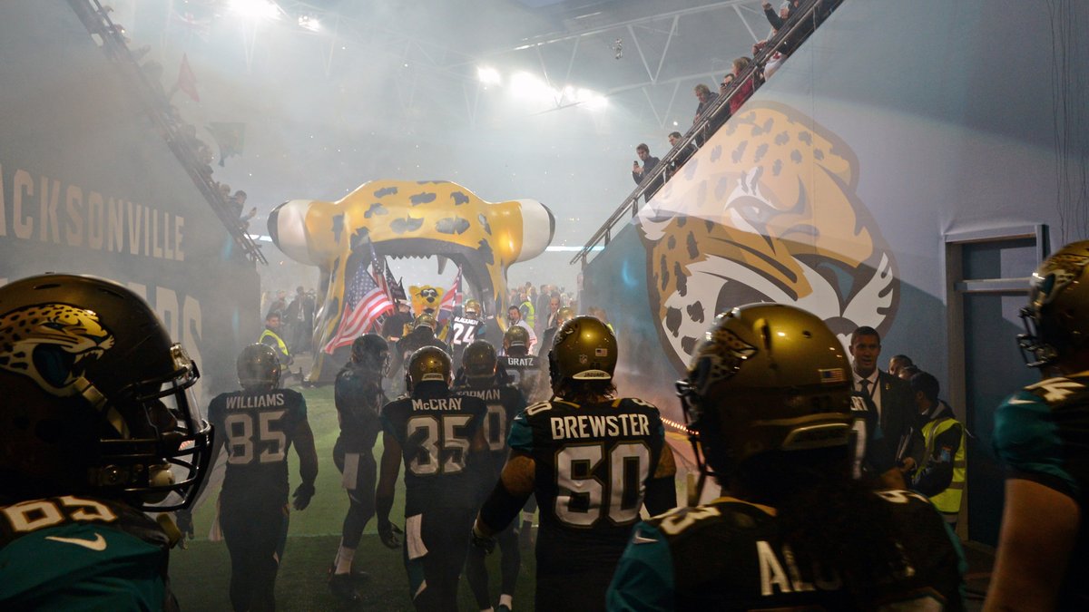 Jacksonville Jaguars players in black and teal wait in a smoky tunnel at Wembley Stadium before a 2013 game in London