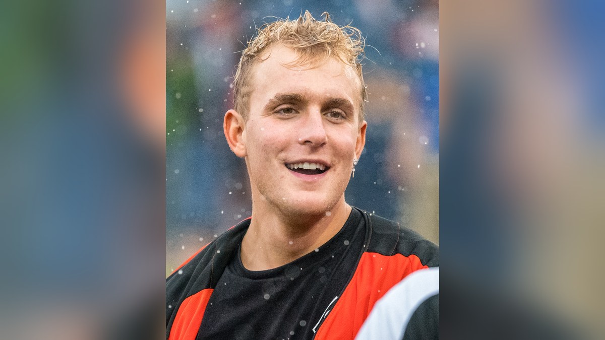 Jake Paul smiling in an orange and black jersey