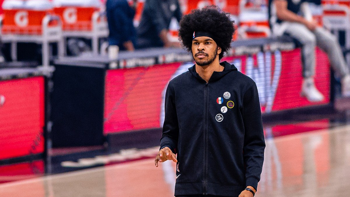 Jarrett Allen in a black Cleveland Cavaliers warmup jacket and headband walks across the court before a game