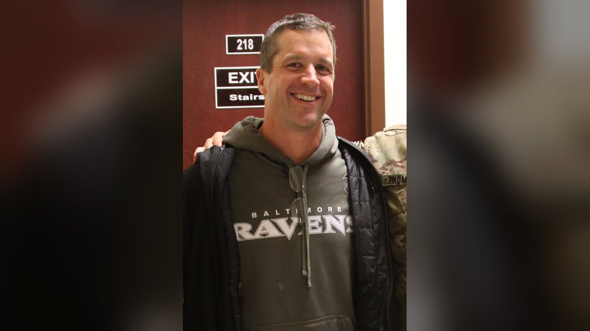 John Harbaugh smiles in a gray Ravens hoodie during a February 2014 visit with U.S. troops at Kandahar Airfield in Afghanistan
