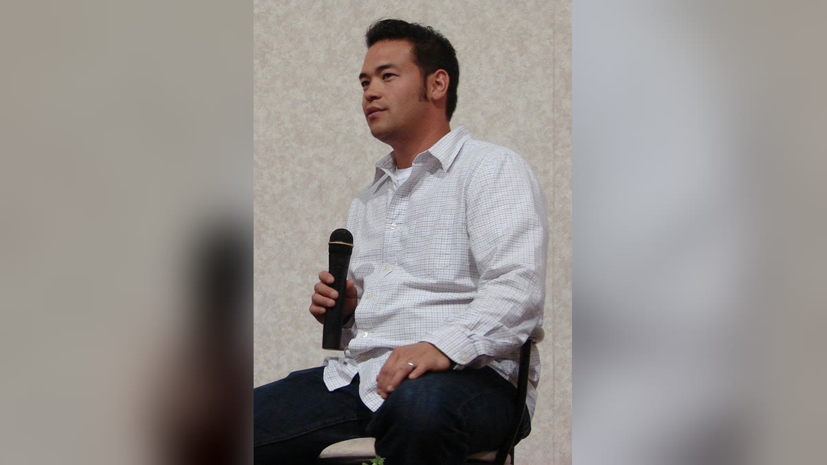 Jon Gosselin in a white checked shirt seated with a microphone