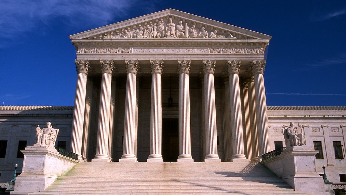 The white marble front of the U.S. Supreme Court building under a deep blue sky