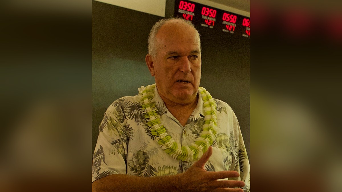 June Jones in a lei and aloha shirt speaking at a conference in Hawaii