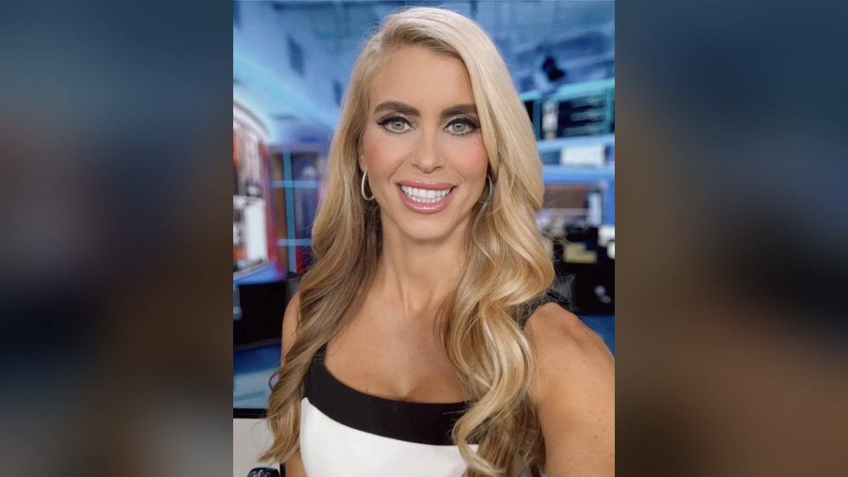 Katie Zacharia smiling with long blonde hair in a black and white top inside a TV studio