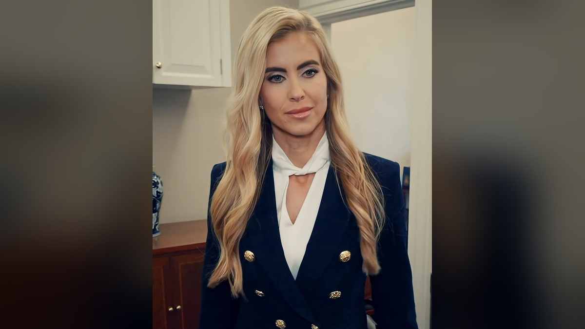 Katie Zacharia with long blond hair in a navy double-breasted blazer and white bow blouse