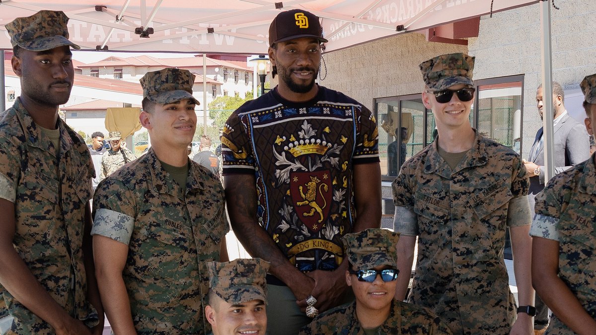Kawhi Leonard smiling in a San Diego Padres cap as he poses with U.S. Marines at Camp Pendleton