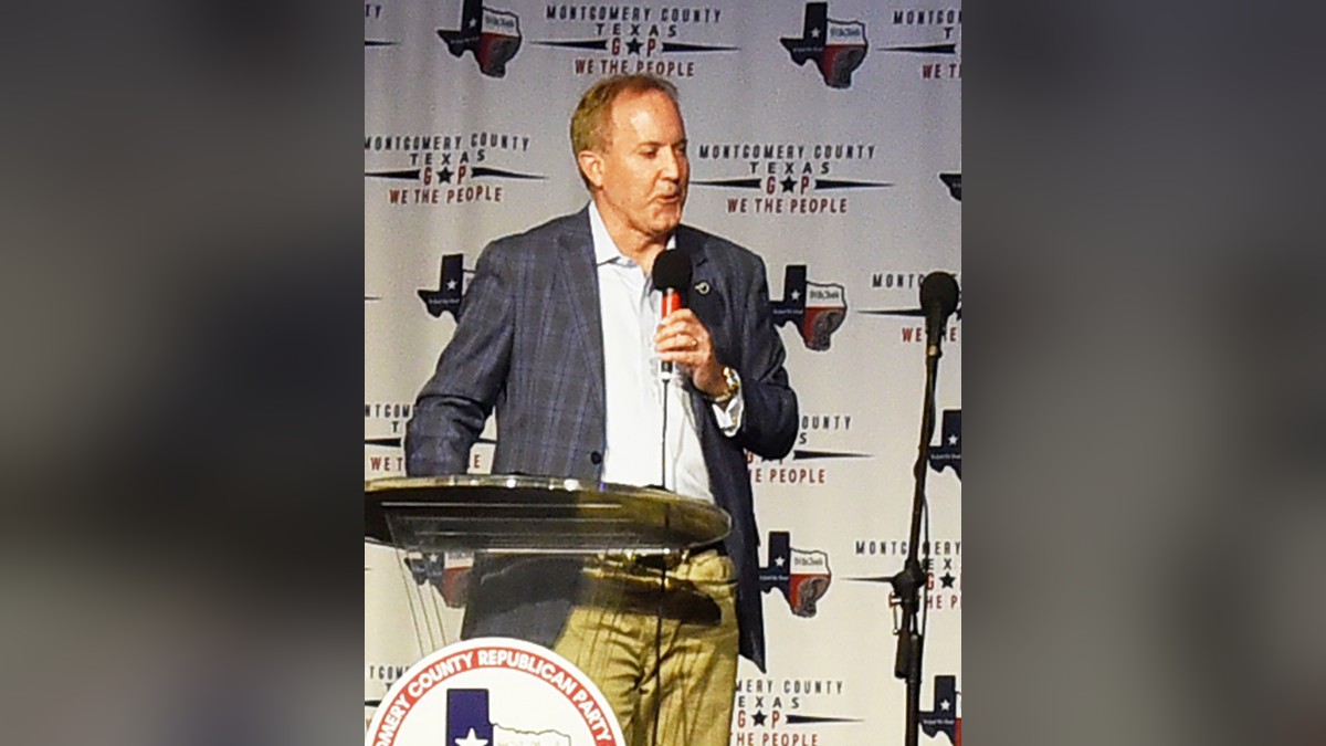 Ken Paxton speaking into a microphone at a podium during a Texas political rally