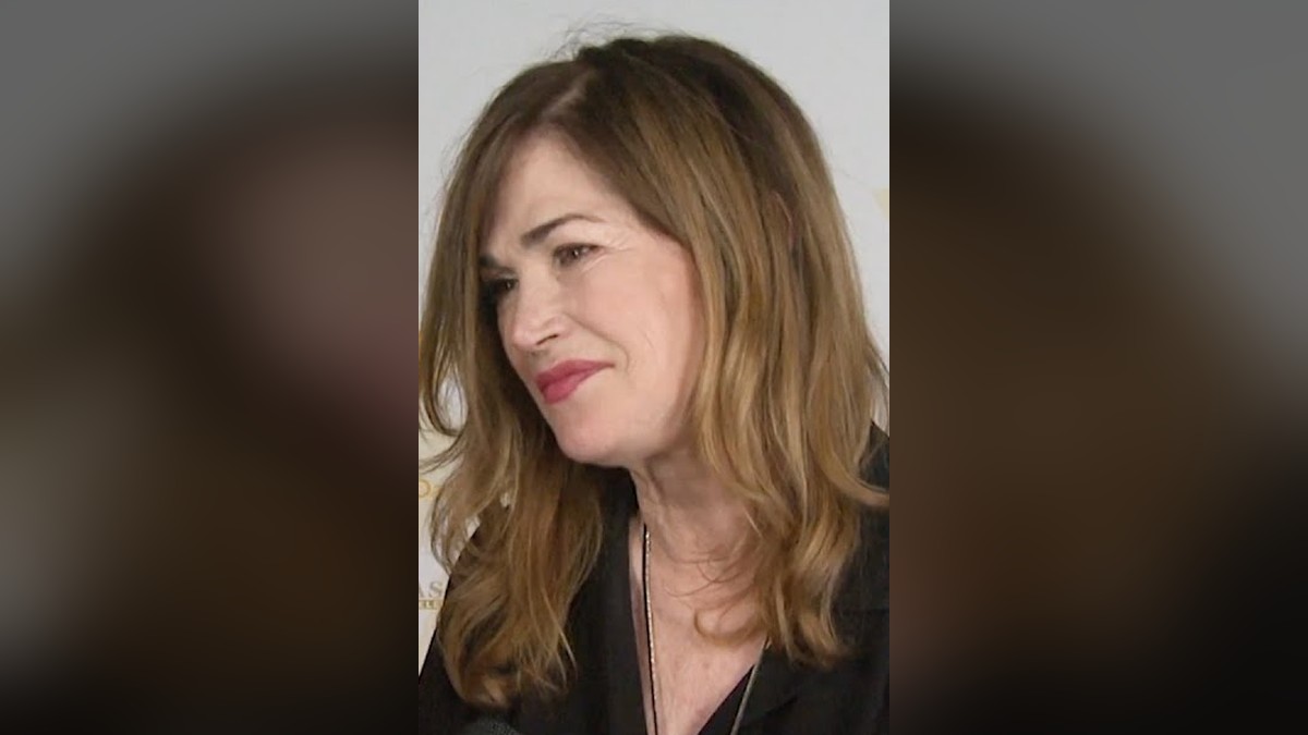 Kim Delaney with long auburn hair smiling during a red carpet interview