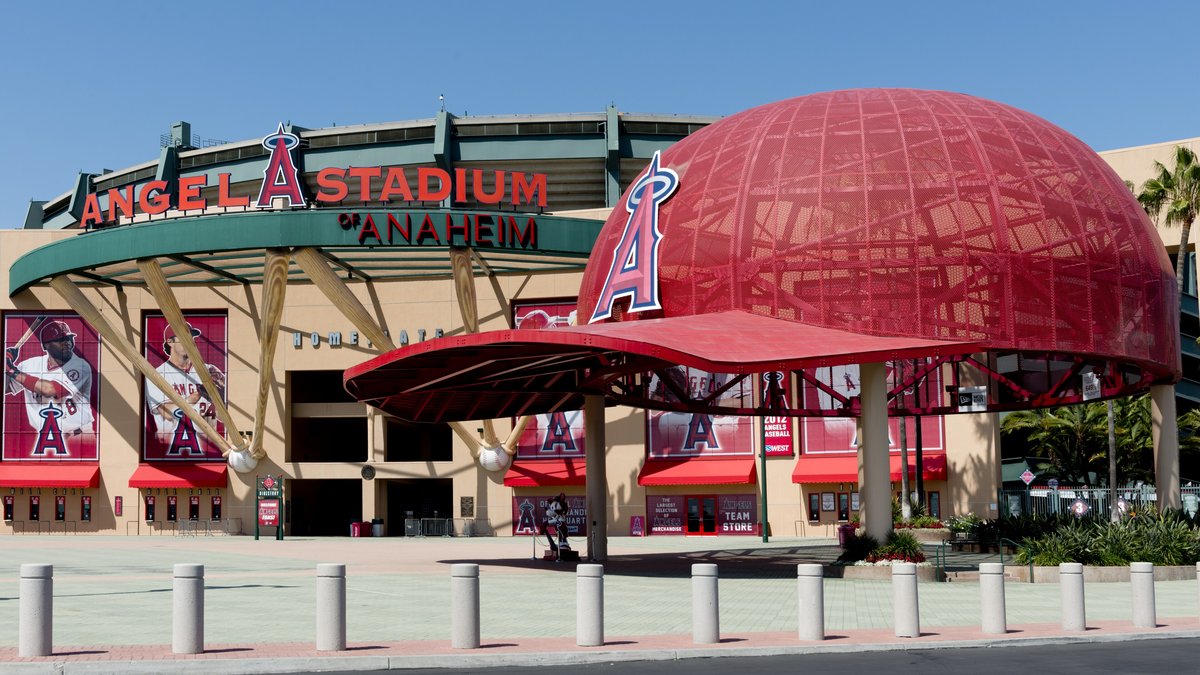 The front of Angel Stadium of Anaheim with its red halo letters and giant red baseball caps under a clear blue sky