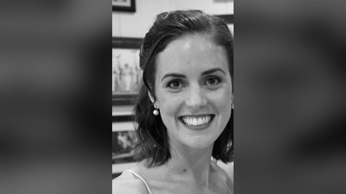 Kyle Kennedy smiling in a black-and-white portrait with pearl earrings