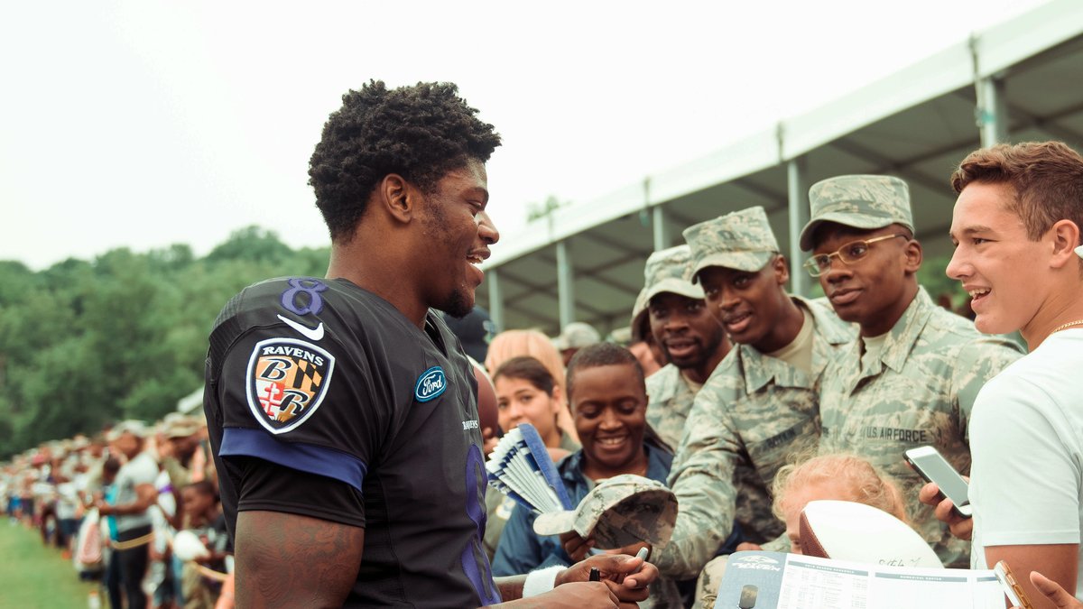Ravens quarterback Lamar Jackson smiles while signing autographs for service members at a 2018 training camp practice