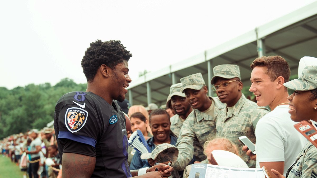 Baltimore Ravens quarterback Lamar Jackson smiles while signing autographs for service members at Ravens training camp in 2018