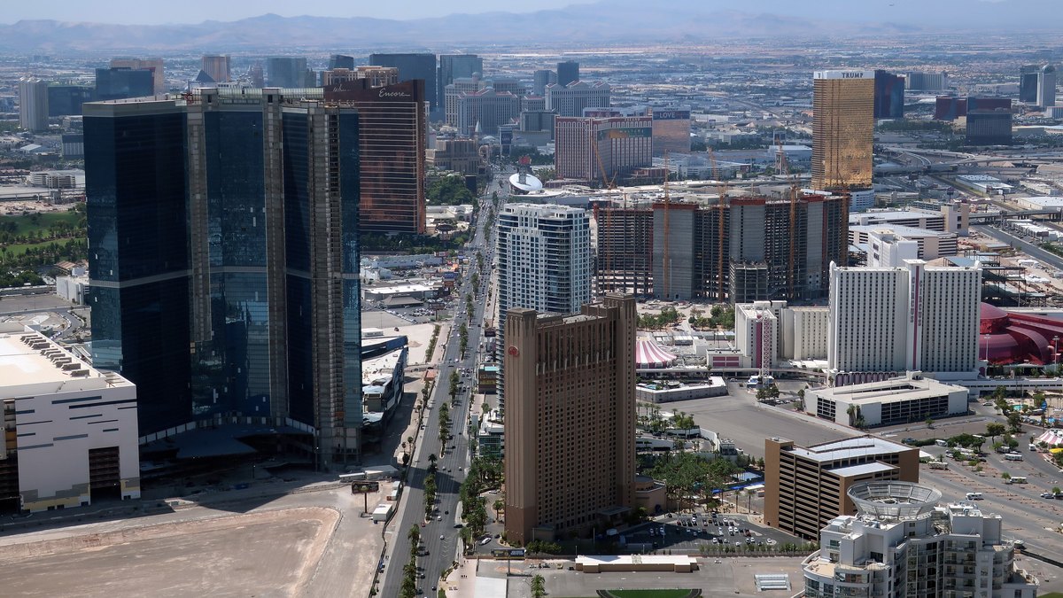 High-rise hotels and office towers spread across the Las Vegas Valley under a hazy sky with mountains on the horizon
