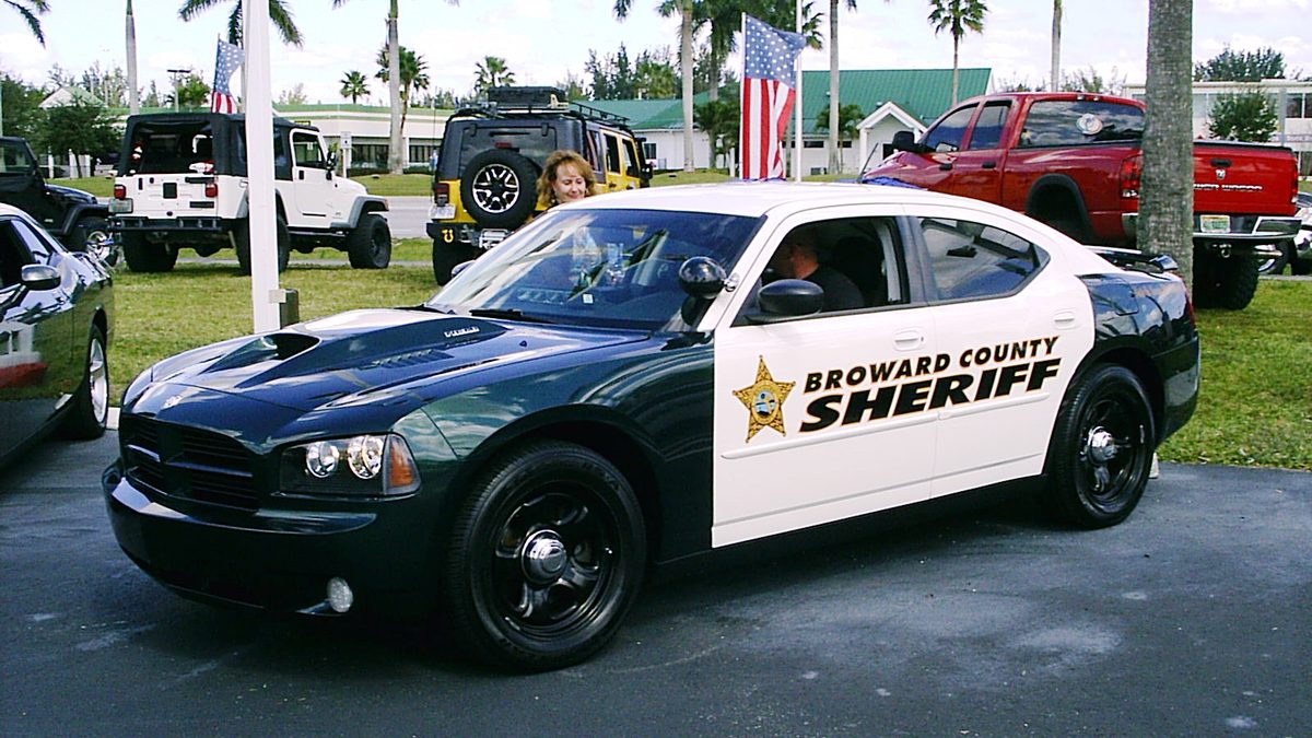 A black and white Broward County Sheriff patrol car parked on a lot under palm trees