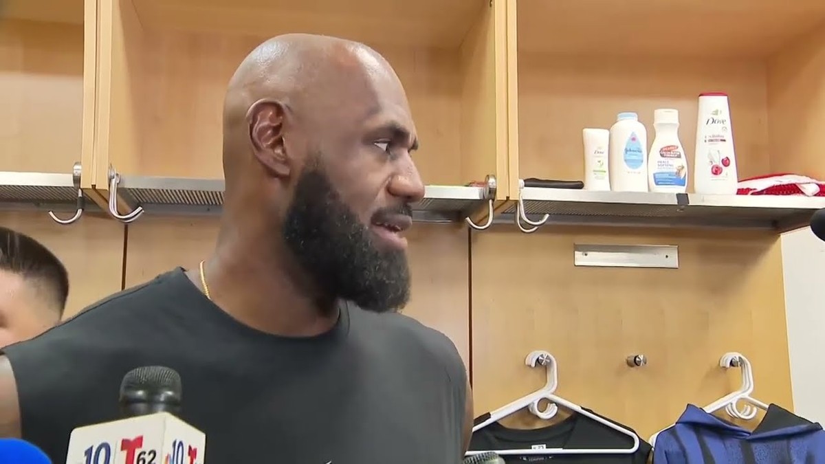 LeBron James with a full beard talking to reporters in a locker room