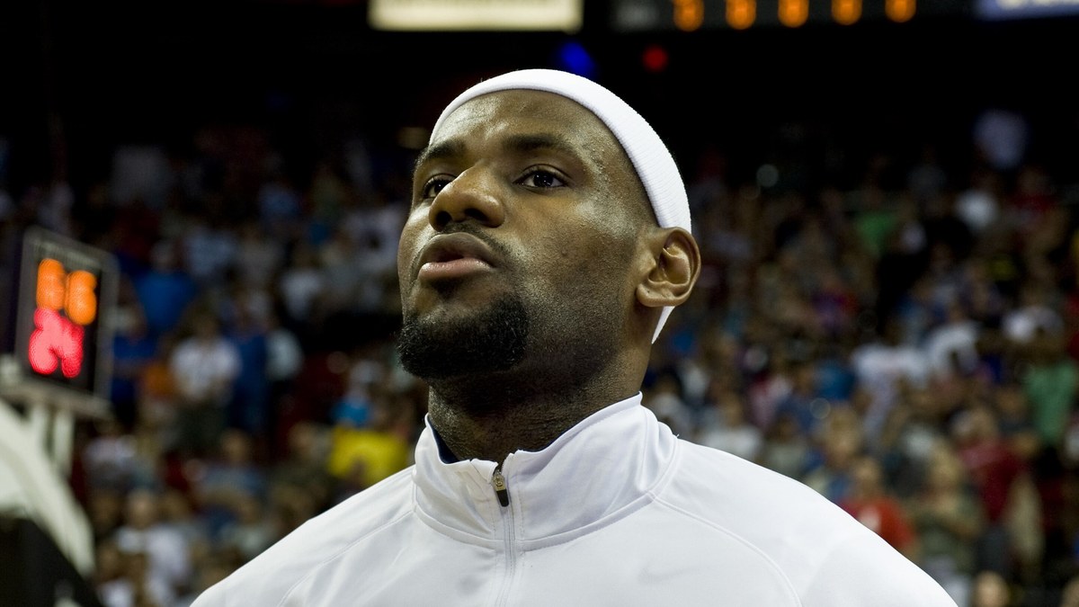 LeBron James in a white warmup jacket looking up during the national anthem before a game