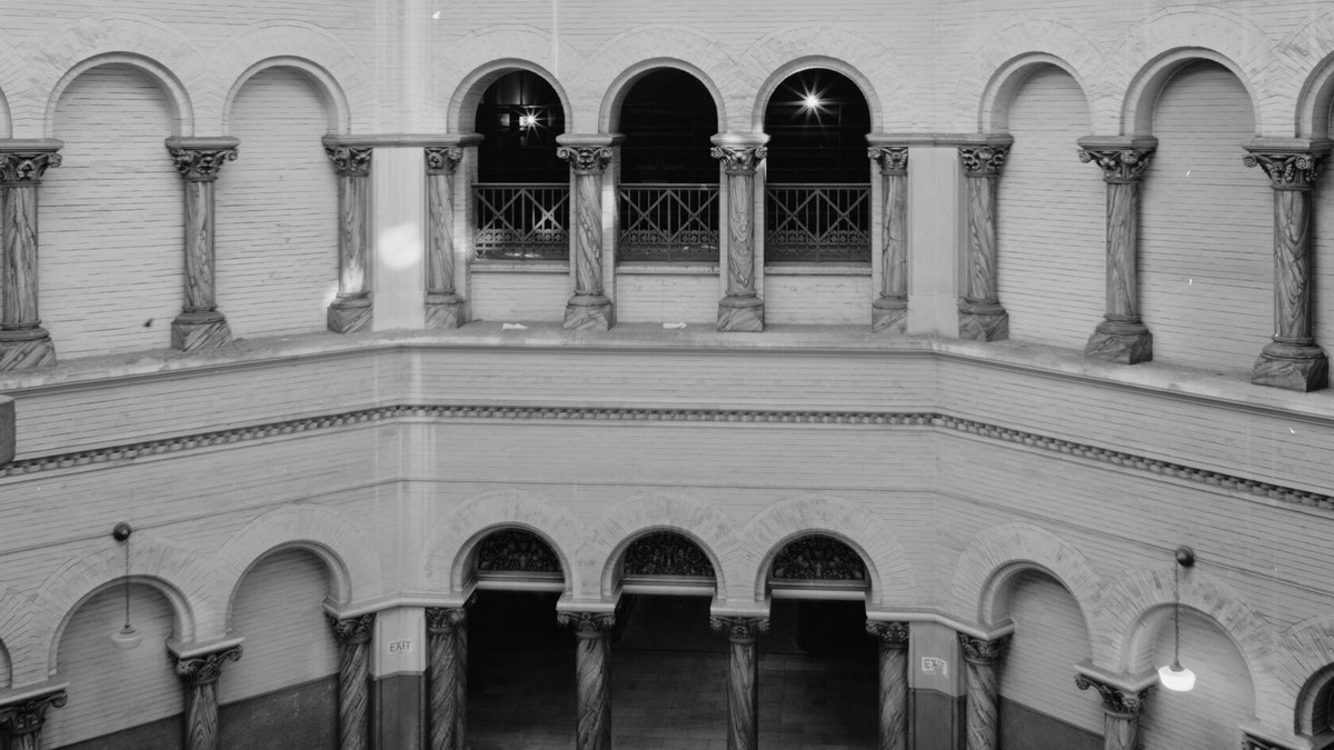 Arched stone galleries and carved columns ringing the rotunda of a historic courthouse