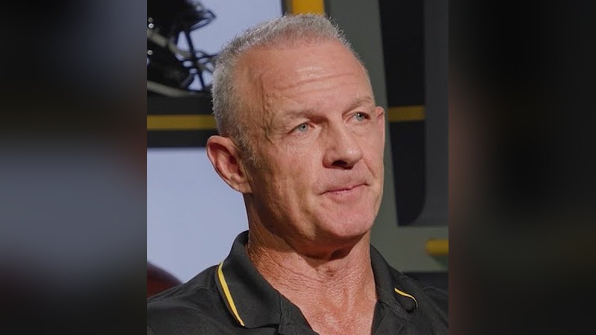 Merril Hoge with short gray hair in a black polo with gold trim during an interview