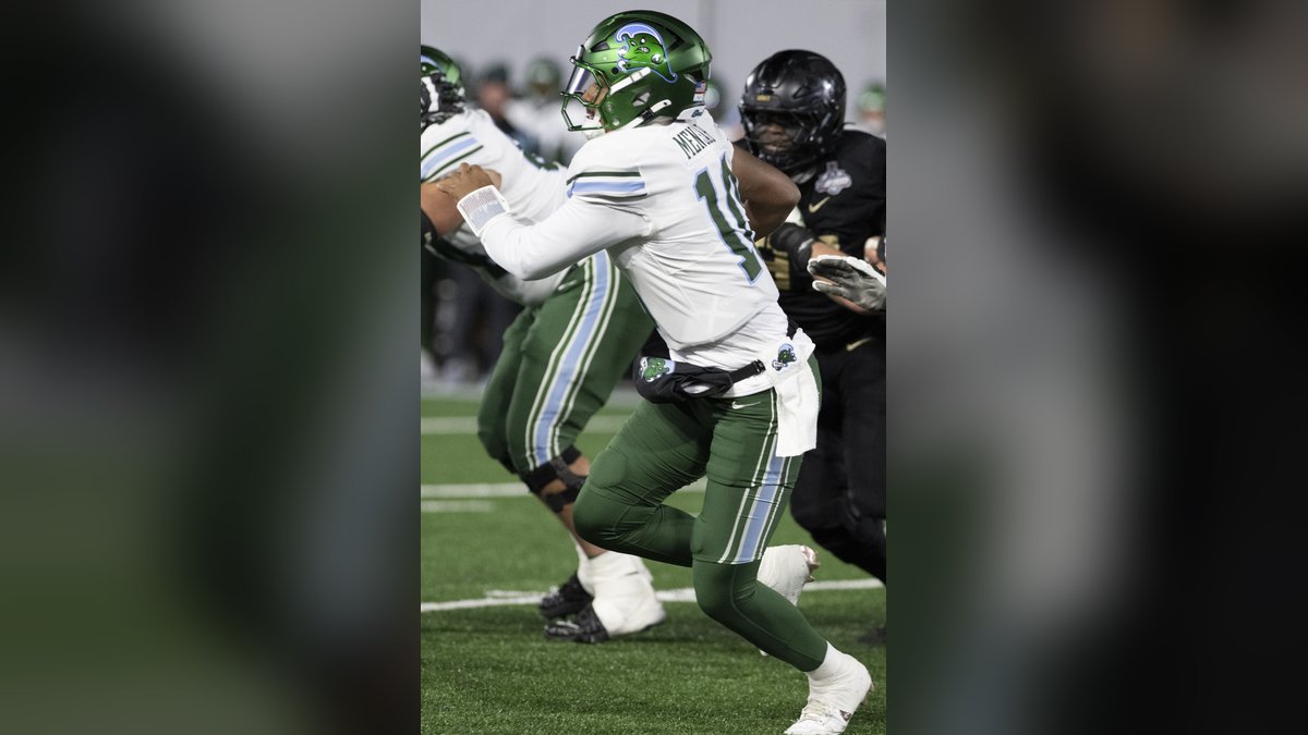 Quarterback Darian Mensah in a white Tulane jersey and green helmet drops back to pass during the 2024 AAC championship game
