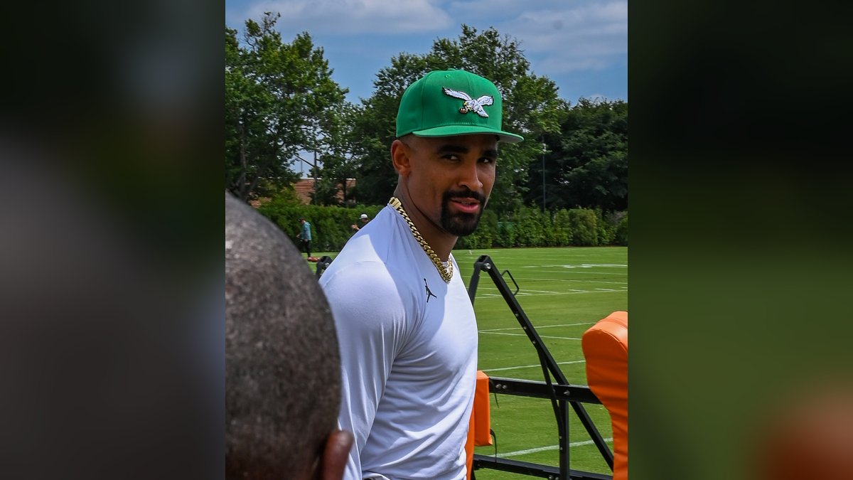 Jalen Hurts in a green Eagles cap and white shirt at Eagles training camp