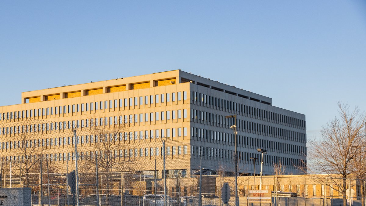 The Bishop Henry Whipple Federal Building near Minneapolis glowing in late-day sun behind a chain-link fence and bare winter trees