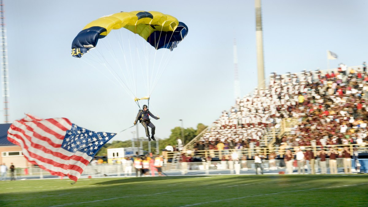 Packed stands at the North Carolina A&T football stadium in Greensboro as a parachutist lands with an American flag