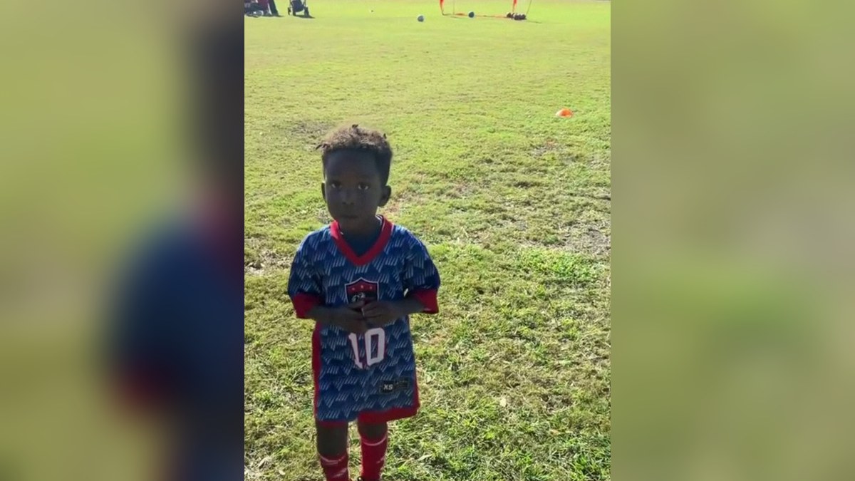 Nevada Pierre, 3, standing on a grass soccer field in his blue number 10 jersey and red socks