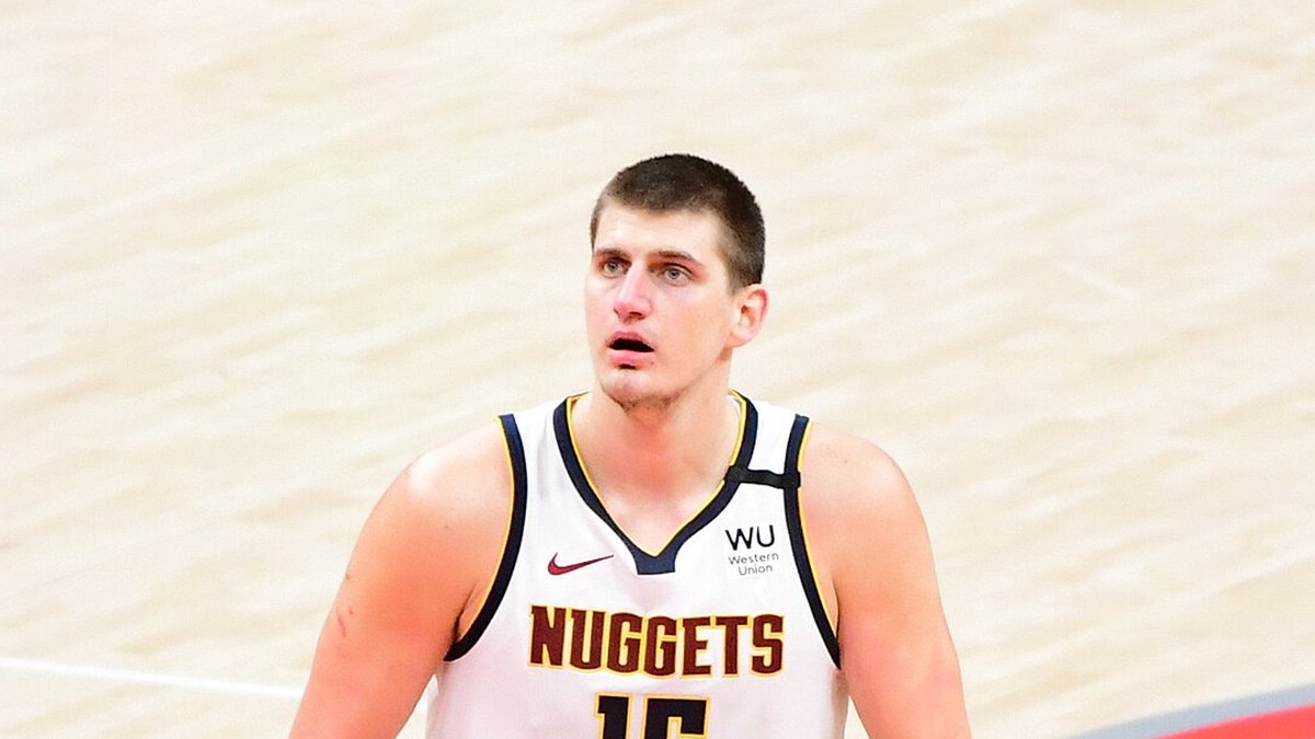Nikola Jokic in a white Denver Nuggets jersey looking up during a game