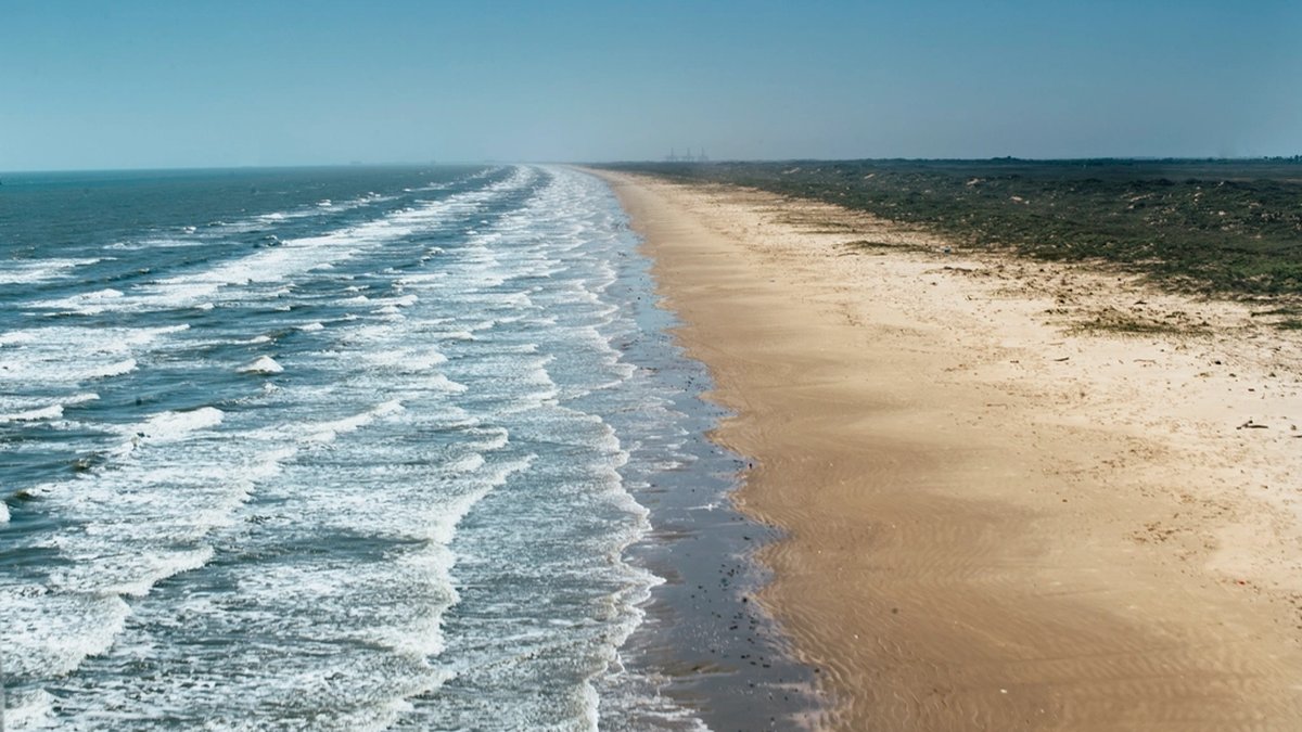 Aerial view of blue ocean waves breaking onto a sandy beach