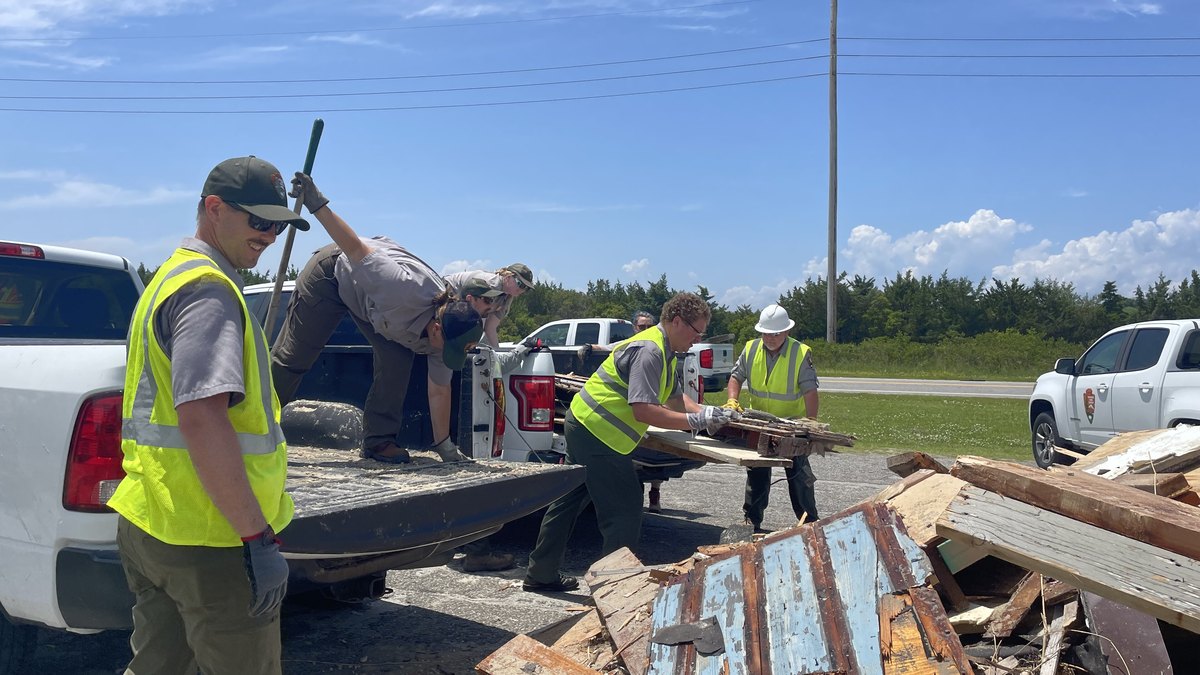 Workers in safety vests load broken lumber from a collapsed oceanfront house onto a truck in Rodanthe on the Outer Banks
