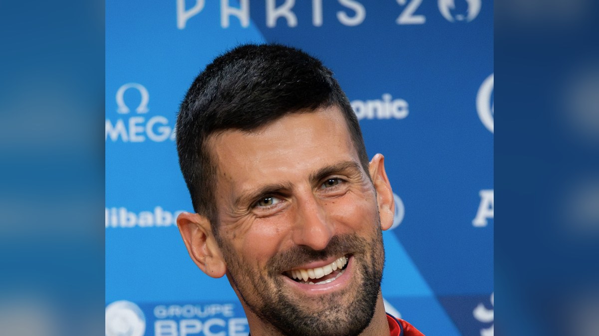 Novak Djokovic smiling at a Paris 2024 Olympics press event
