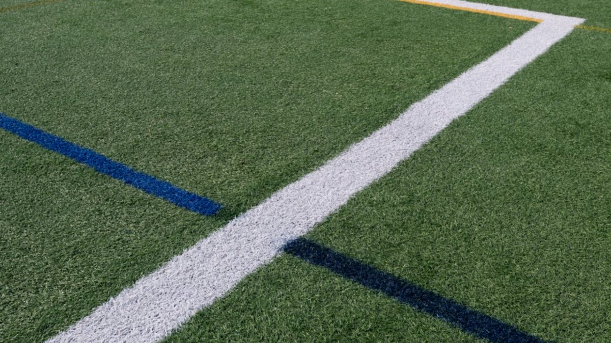 White and blue lines cross on green artificial turf