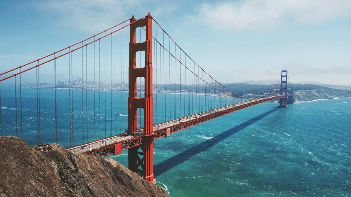 Aerial view of the Golden Gate Bridge and San Francisco Bay under a bright sky