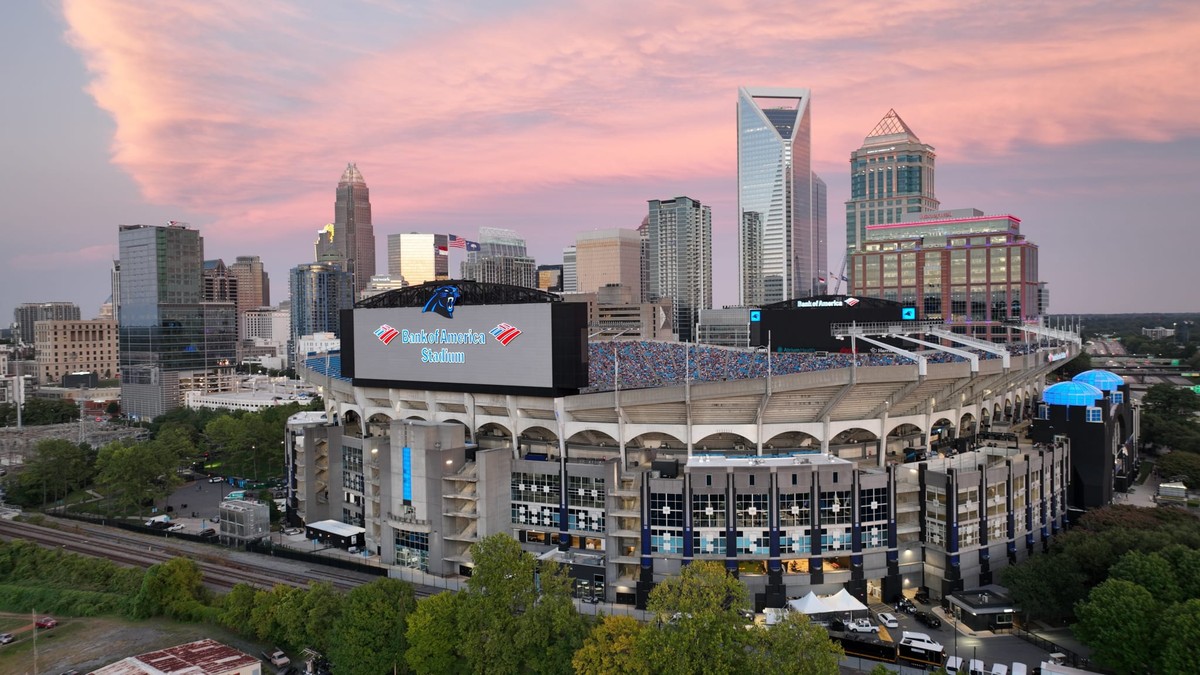 Bank of America Stadium, home of the Carolina Panthers, in front of the Charlotte skyline under a pink sunset sky
