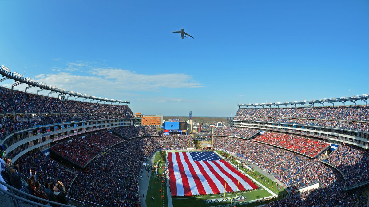 A military cargo plane flies over a packed Gillette Stadium in Foxborough as a giant American flag covers the field before a November 2012 game