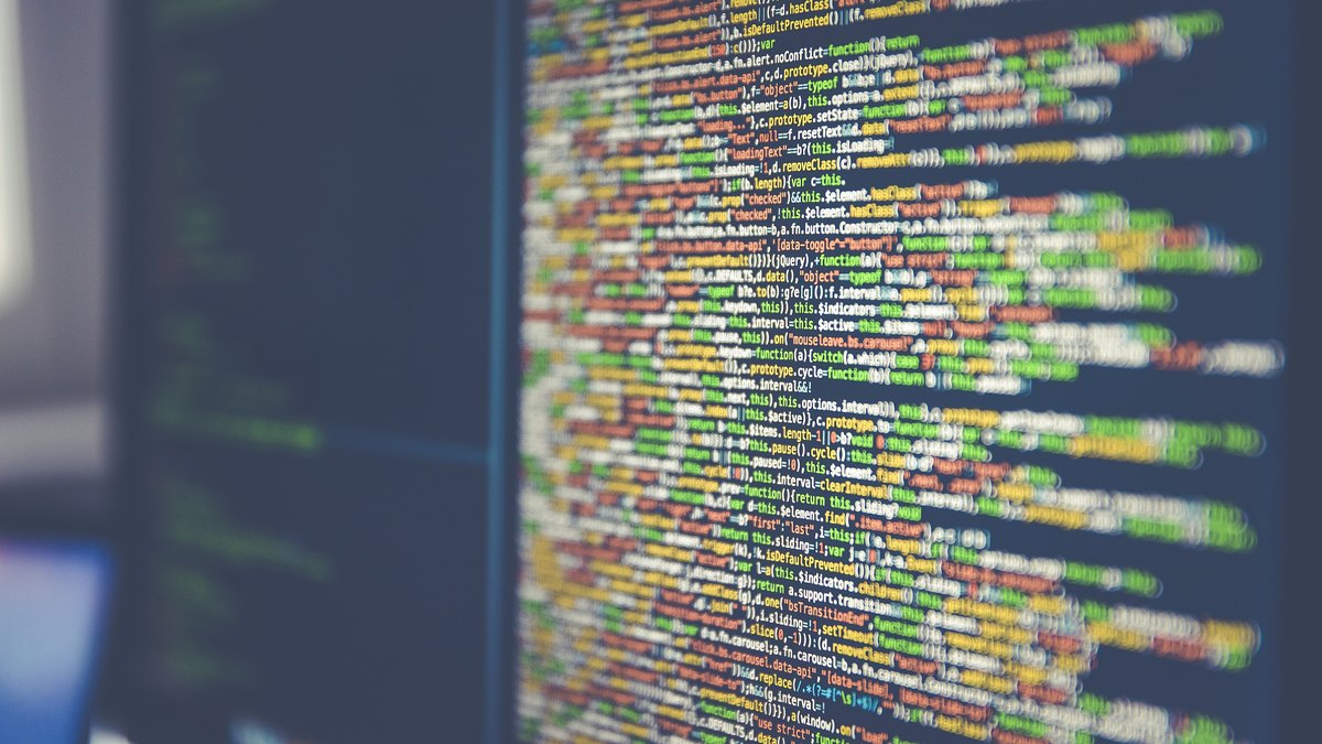 Lines of colorful programming code fill a dark computer monitor in a close view of a developer's screen