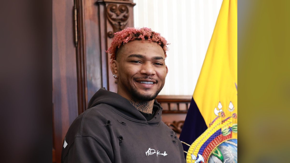 UFC welterweight Michael Morales smiling beside the flag of Ecuador during a visit to the presidential palace in Quito