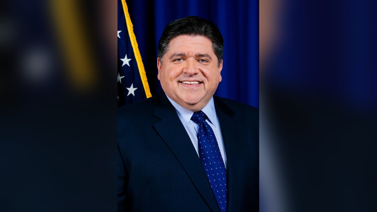 Illinois Gov. JB Pritzker smiles in an official portrait in front of an American flag and a dark blue backdrop
