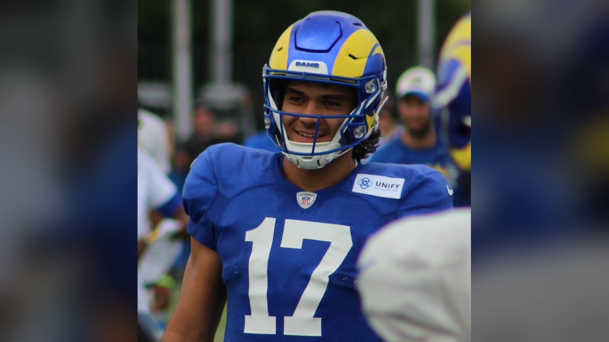 Puka Nacua smiling in his Rams helmet and blue No. 17 practice jersey at training camp