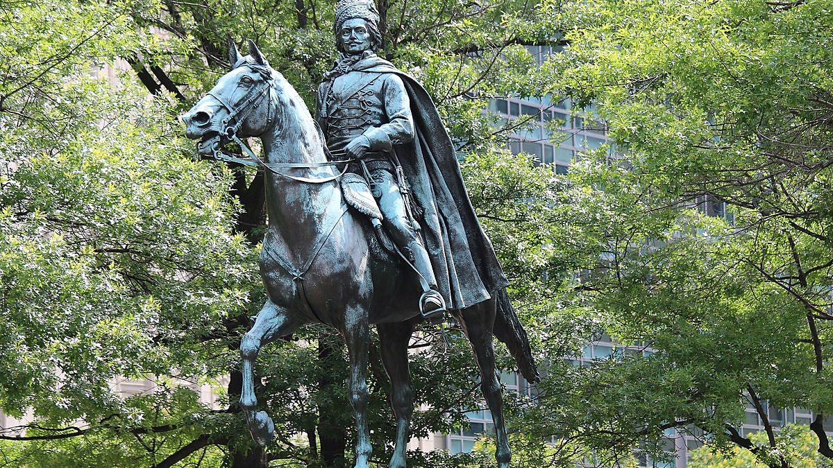 Bronze equestrian statue of Gen. Casimir Pulaski framed by green trees in Washington, D.C.
