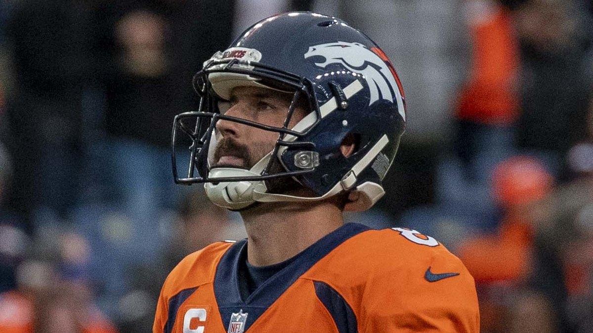 Kicker Brandon McManus in a Denver Broncos helmet and orange No. 8 jersey looks up the field during a 2021 home game