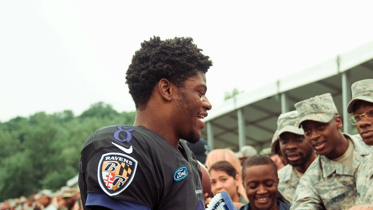 Ravens quarterback Lamar Jackson smiling as he greets Air Force members along the fence at Baltimore Ravens training camp in 2018