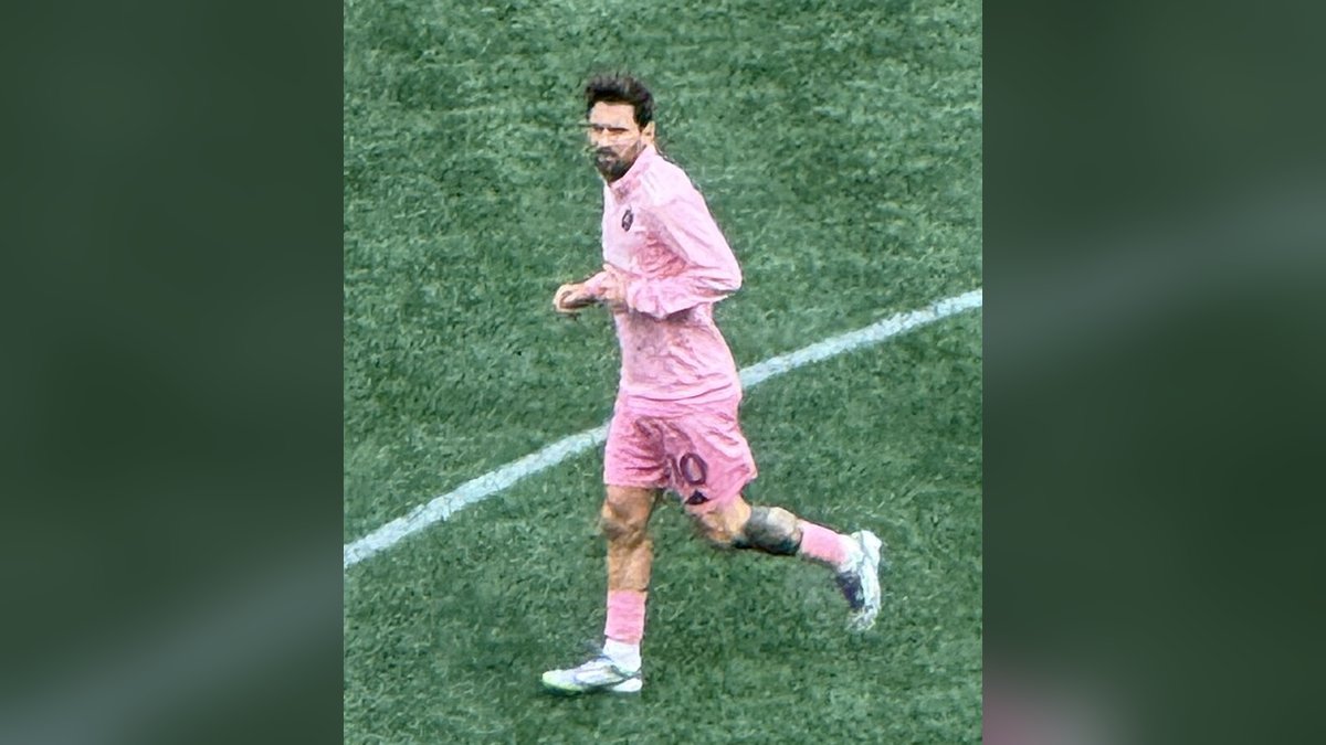Lionel Messi in a pink Inter Miami kit jogging across the field during warmups